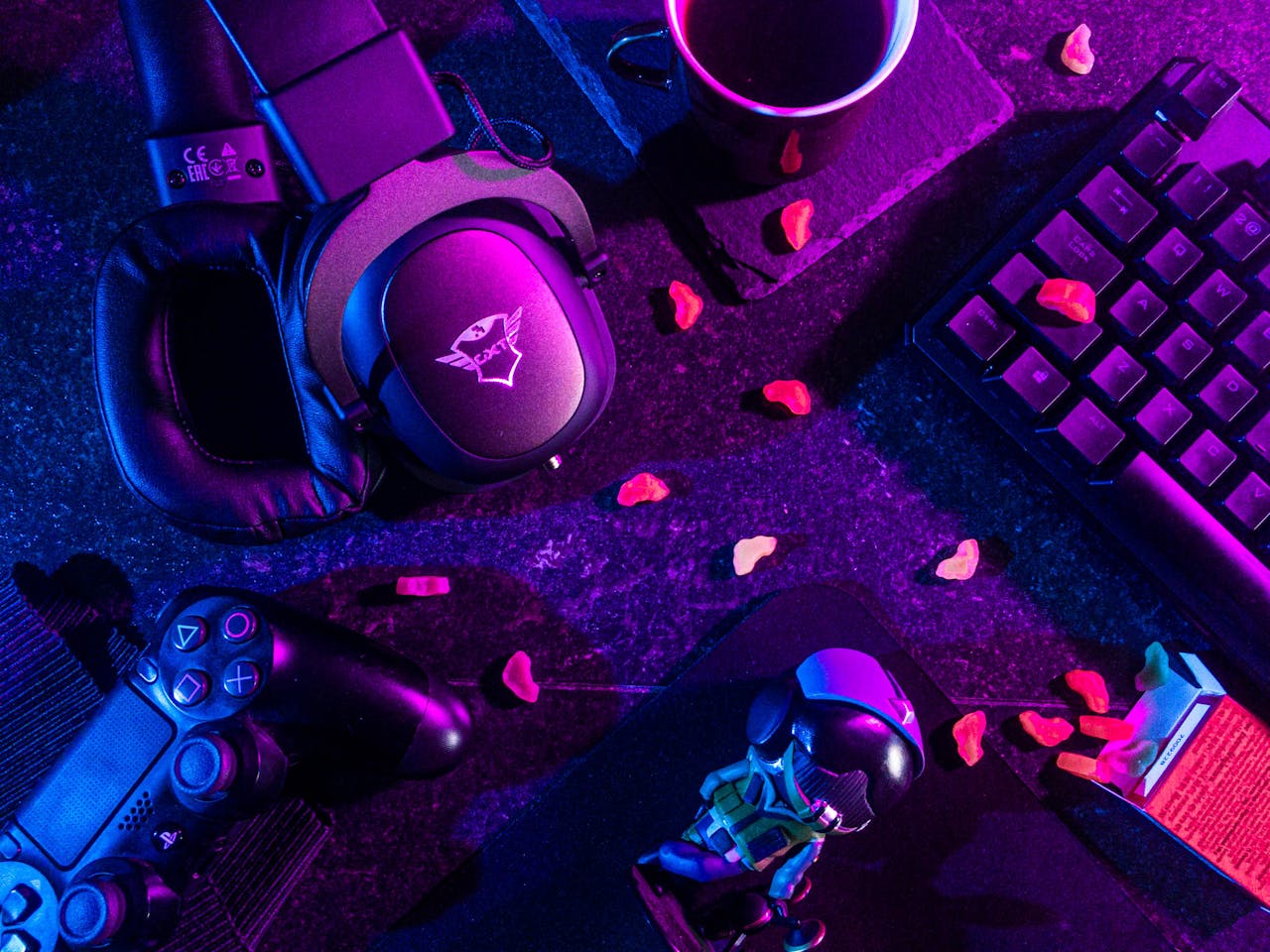 Services Colorful flat lay of gaming gear including headset, controller, and keyboard under vibrant lighting.
