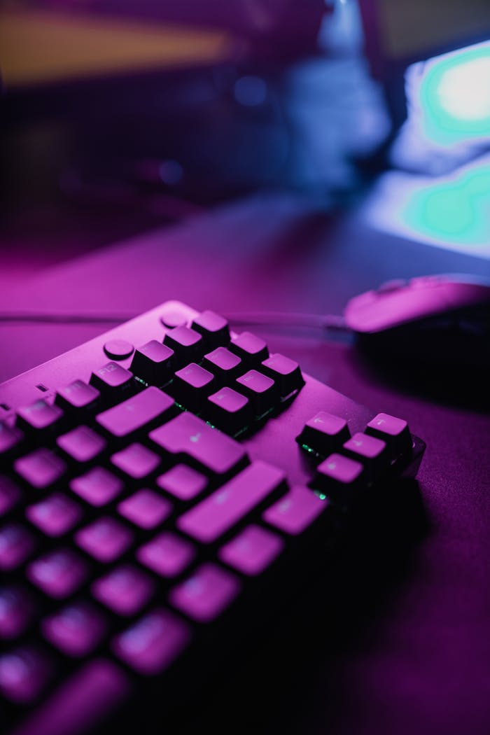 Services Close-up of a gaming keyboard and mouse illuminated by vibrant pink lighting, creating a dynamic atmosphere.